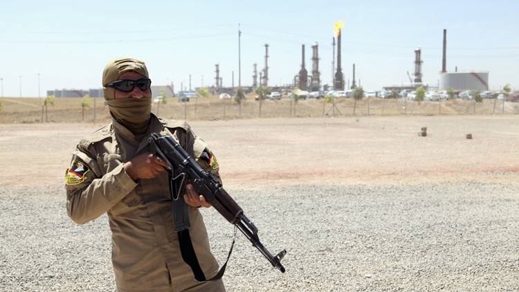 A member of Kurdish security forces takes up position with his weapon as he guards an oil refinery on the outskirts of Mosul